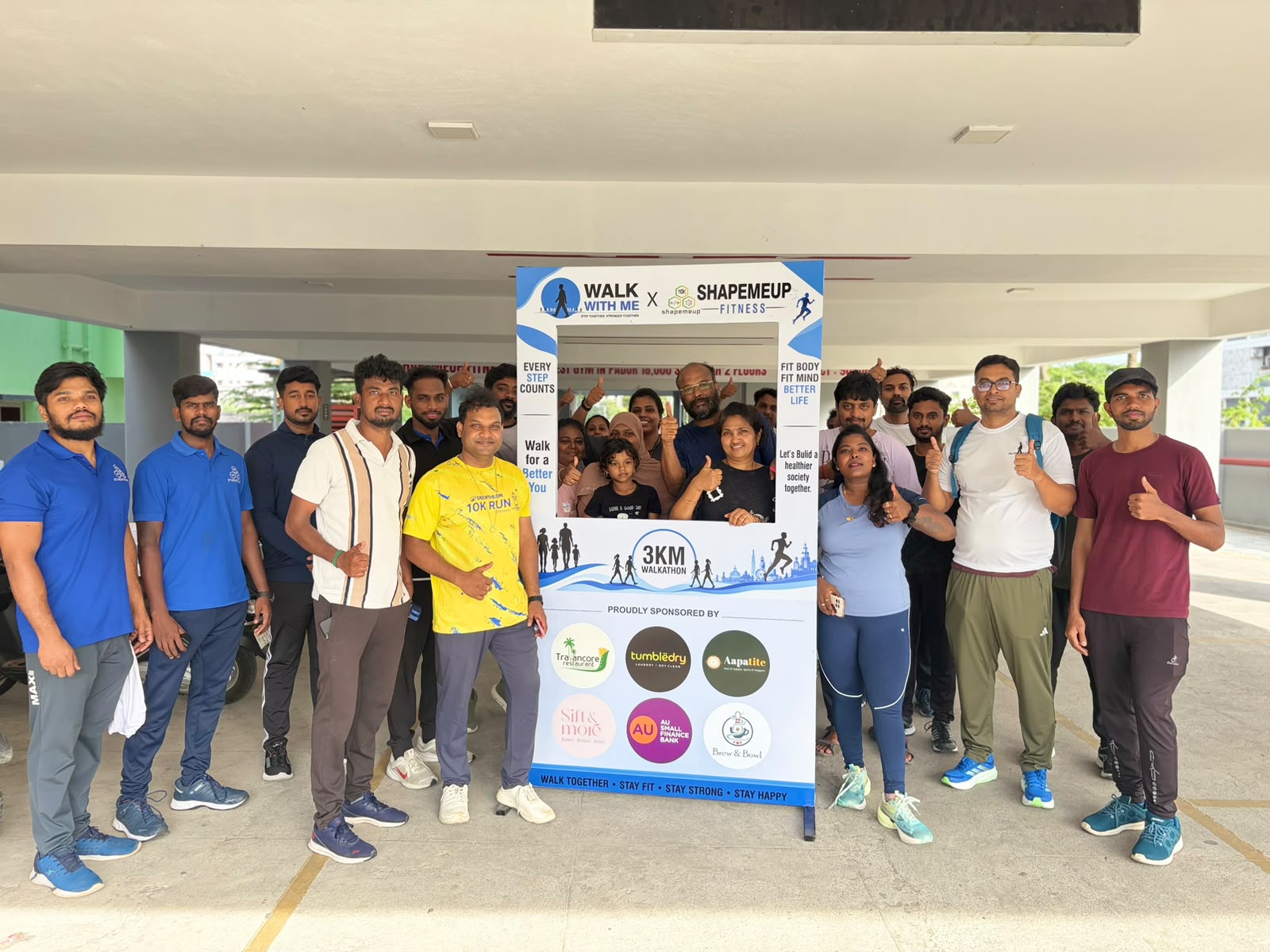 Students, fitness enthusiasts and members of the public pose at the Walk With Me walkathon photo frame in Padur