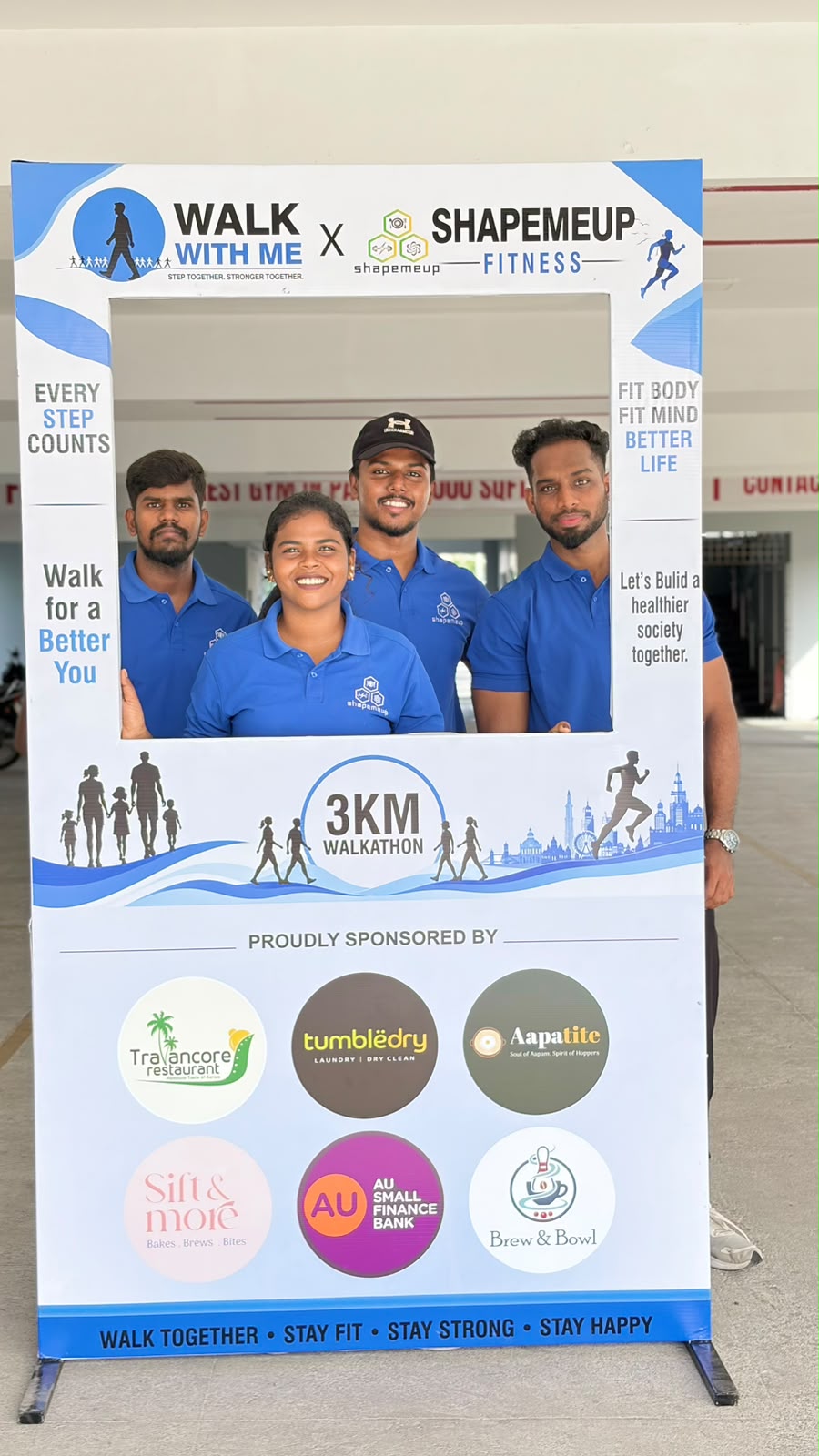 Shapemeup Fitness Studio organisers pose with the Walk With Me selfie frame and sponsor logos
